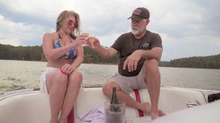 Kelly and Greg, toasting glasses of champagne while sitting on a boat, in episode 1 of THE LATER DATERS.