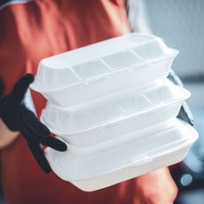 delivery woman with protective medical mask and gloves holding food box