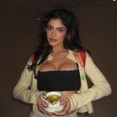 Kylie Jenner wears a bandeau top with a cup of tea