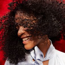 A woman smiles as she flicks her hair from side to side.