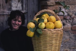 A woman poses in Calabria, Italy with a big basket of lemons.