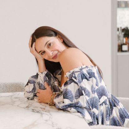 Sara Naghedi poses in an off-the-shoulder dress in her work-from-home office