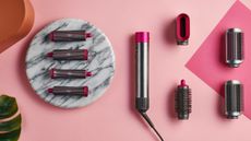 The Dyson AirWrap, one of the best hair curlers, on a pink and marble table