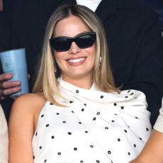 Margot Robbie in the stands at Wimbledon wearing the black and white polka dot dress trend in the form of an Alaïa dress