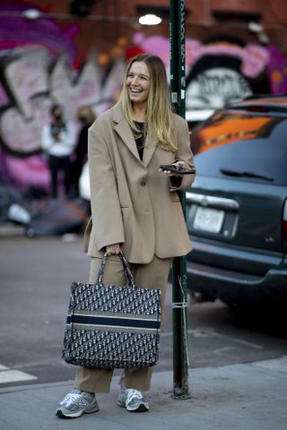 woman wearing brown suit set and a Christian Dior designer tote bag