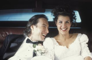 a couple in a suit and wedding dress smiling in the backseat of a car in my big fat greek wedding