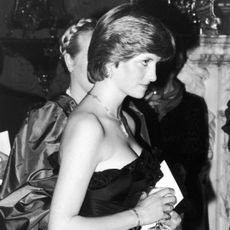 Princess Diana wearing a black strapless evening gown and turning to the right side looking serious