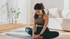 A woman doing the butterfly stretch in her living room