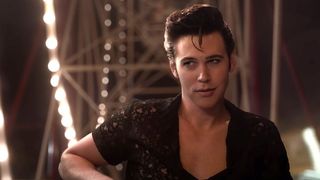 Austin Butler stars as Elvis Presley with his hair in the iconic look and in a black shirt at a carnival in 'Elvis'