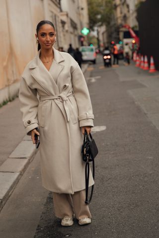 woman wearing double breasted coat, pants, and sneakers