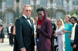 christopher walken in a suit and grace jones in a red hooded dress in the james bond movie a view to kill