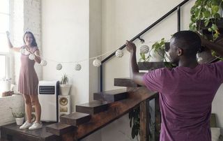 Young couple decorating loft with fairylights