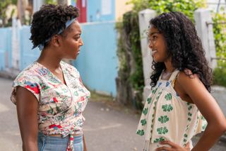 lashay anderson and mia isaac as two girls talking to each other on the streets of jamaica in black cake