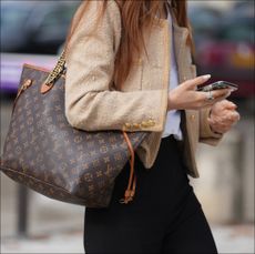 A guest wears a beige tweed jacket, a Vuitton large bag, black pants, outside Chanel, during the Womenswear Spring/Summer 2024 as part of Paris Fashion Week on October 03, 2023 in Paris, France. 