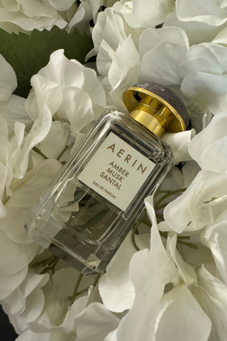 Aerin's Amber Musk Santal on a bed of white flowers.