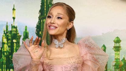 Ariana Grande on the wicked red carpet wearing a pink tulle dress and a french manicure referencing her character Glinda