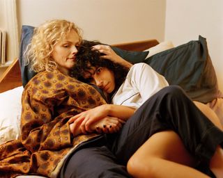 a blonde woman comforts another woman laying next to her in bed in the tv show 'The Bisexual'