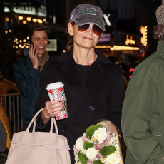 katie homles wears a black topcoat and white sneakers