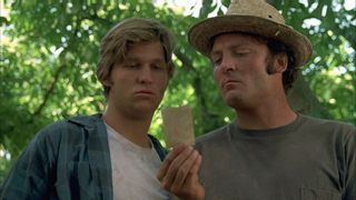 two men look at a piece of paper while outdoors in fat city