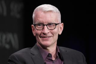 anderson cooper wearing glasses and a black jacket promoting his podcast All there is