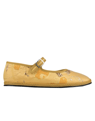 a yellow mary jane slipper with brocade fabric on a plain backdrop