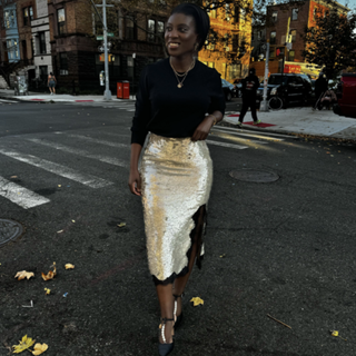 Nikki Ogunnaike wearing J.Crew's Cashmere Classic-Fit Crewneck Sweater, Gwyneth Lace-Trim Slip Skirt, and Made-In-Spain Jules Pearl-Strap Pumps in Satin.