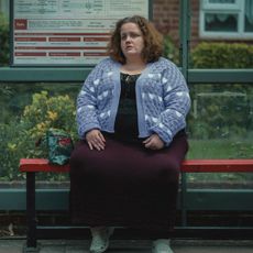 Jessica Gunning as Martha, sitting at a bus stop, in the Netflix series 'Baby Reindeer'