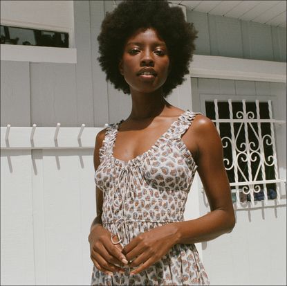 Model wearing white, red, and blue patterned smocked Dôen dress with a white background.