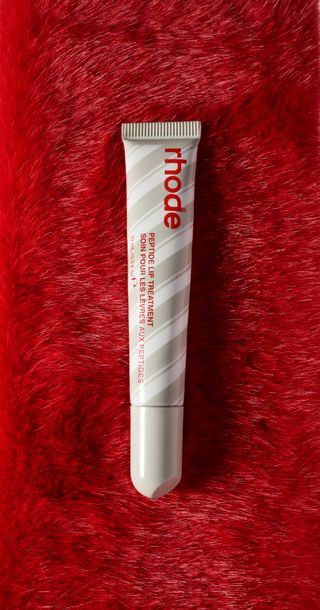 A closeup of a striped tube of Rhode Peppermint Glaze Peptide Lip Treatment