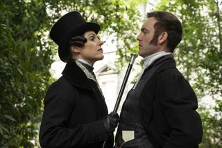 a woman dressed in top hat points a cane under a man's chin in a still from Gentleman Jack