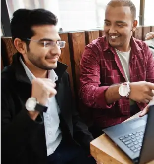 a couple of men sitting at a table with laptops