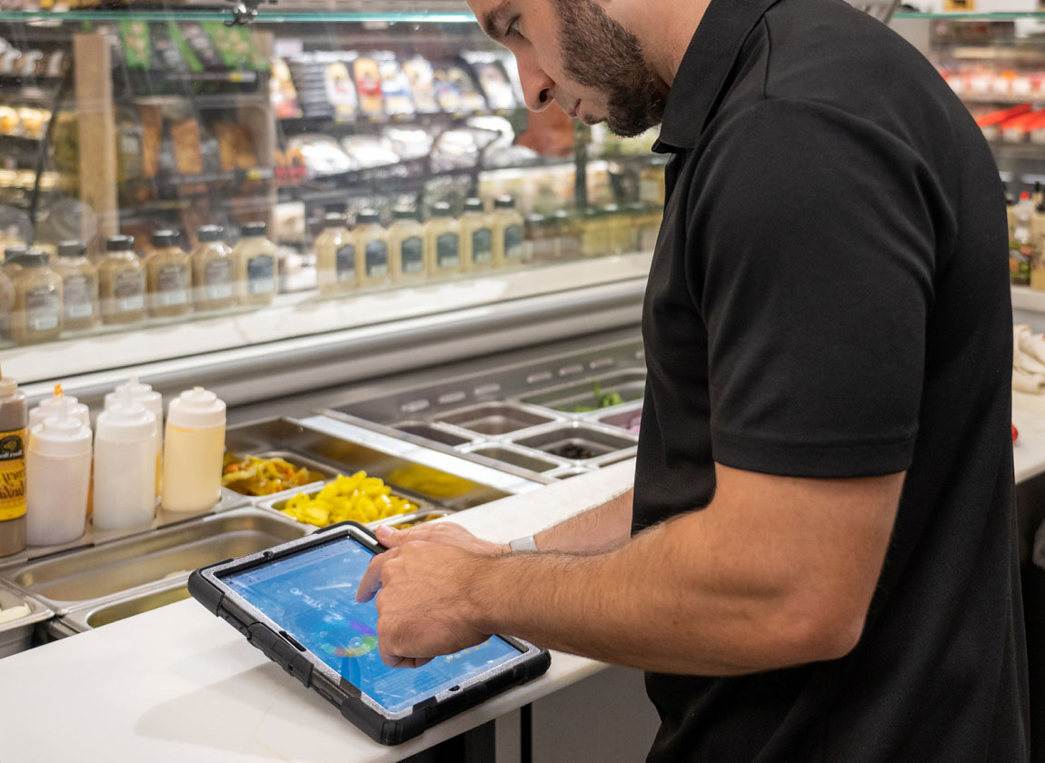 dark haired man using FoodStorm application on a tablet