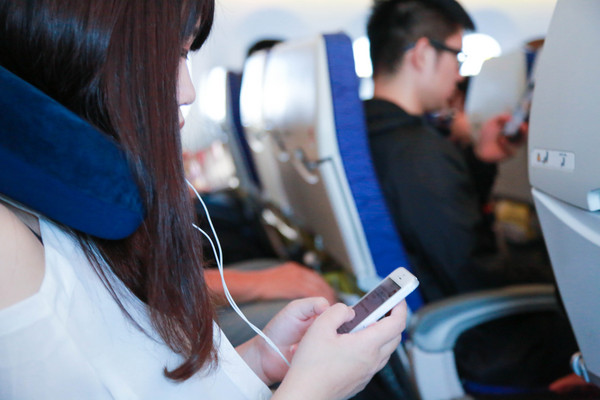 飛機上使用3c產品,飛機上滑手機,飛機上玩手機,飛機上聽音樂,戴耳機（圖／記者林世文攝）