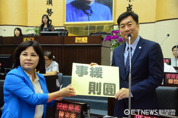 ▲國民黨團砲聲隆隆，民進黨市議員賴惠員拿「事緩則圓」牌子送民政局長陳宗彥。（圖／記者林悅攝）