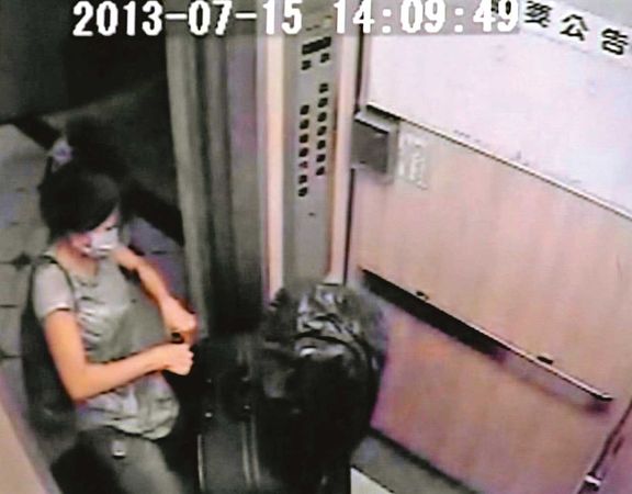 林女拉著沉重的行李箱出門，行李箱內疑似裝著陳男的屍體。（翻攝畫面）