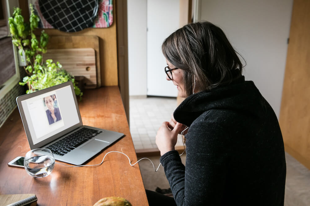 Woman seated at table with laptop computer and headphones, participating in CZI Grant Partner Training Session.