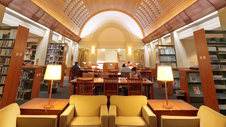 The study floor of a university library with stacks, tables, and chairs