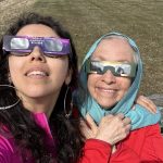 A mother and daughter wearing eclipse glasses.