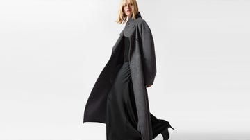 a model walks in a long grey coat over a black outfit