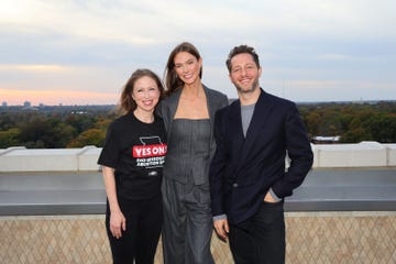 group of three people posing on a rooftop at sunset