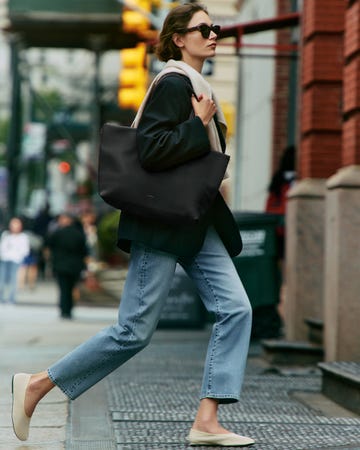 person walking on a city street holding a black tote bag