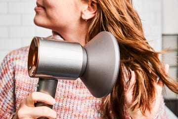 a person using a dyson hairdryer on their hair