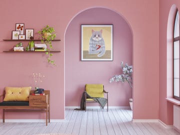 a room with a pink wall and a chair and a shelf with pictures