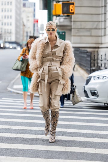 new york, new york february 12 devon windsor wears beige button up jacket, pants with side pockets, animal print knee high boots, fleece fur coat outside puppets puppets during new york fashion week on february 12, 2023 in new york city photo by christian vieriggetty images