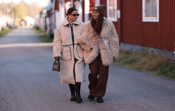 lulea, sweden october 18 benthe liem l seen wearing a black sunglasses, silver pearl earrings, white cream fluffy long coat with black contrast seams, beige black logo pattern bag and copenhagen studios cph138 vitello black leather high boots amaka hamelijnck r seen wearing brown beanie, beige fluffy oversized short coat, brown wide leg pants, white leather crossbody bag and copenhagen studios cph134 vitello black leather boots, on october 18, 2023 in lulea, sweden photo by jeremy moellergetty images for copenhagen studios