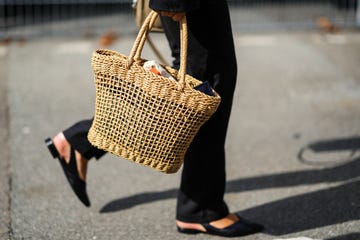 a fashion week guest carries a woven tote bag in a guide to the best woven tote bags of 2023