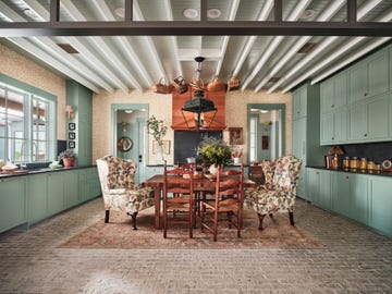 the gathering room dining room table that seats six in the kitchen decorated with leaf motif wallpaper, traditional wingback chairs bought upholstered from an online consignor, blue green paint on the cabinetry and ceilings, and a dark quartz countertop and backsplash appliances signature kitchen suite fixtures elkay countertop and backsplash caesarstone table and range hood grothouse paint farrow  ball wallpaper morris  co lighting circa lighting rug turkish carpets inc door handle schlage