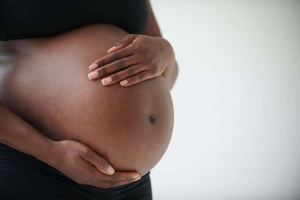 midsection of pregnant black woman holding belly