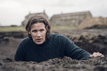 actor matt smith in jumper climbs out of large hole in field