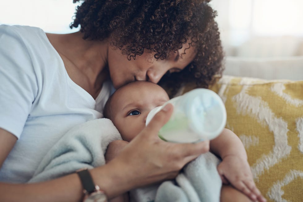 shot of an adorable baby girl being bottle fed by her mother on the sofa at home